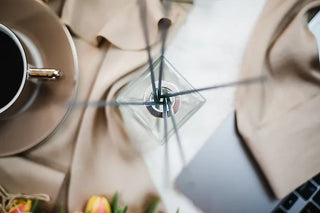 An aesthetic photo of a James and Co Fragrance reed diffuser next to a laptop and a teacup and saucer.