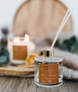 James & Co Fragrance's gingerbread candle is lit out of focus in the background, while a gingerbread reed diffuser sits in the foreground, giving a cosy, autumnal aesthetic.