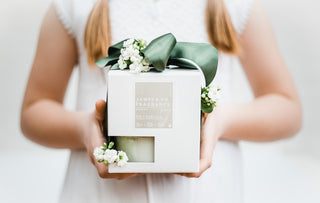 A young woman recieving a Valentines Day gift - it's the James and Co No. 7 Vanilla candle wrapped in a green bow.