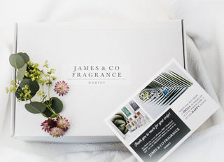 One of James and Co Fragrance's candle and reed diffuser gift boxes with a sprig of eucalyptus plant and a 'thank you' note on top.