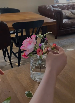 The arm of a young woman upcycling her old glass reed diffuser by making it into a vase.