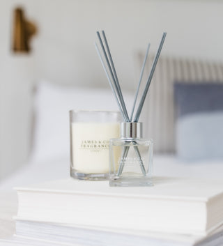 A square diffuser bottle, sitting on a pile of white books.
