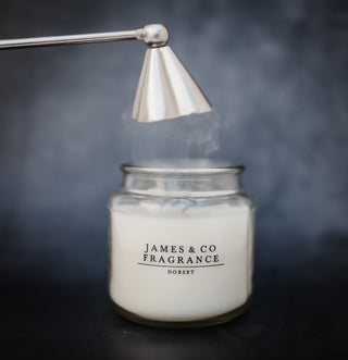 Silver-tone snuffer extinguishing a candle flame