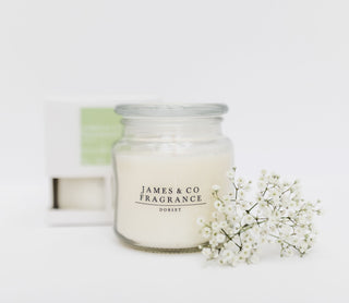 A glass jar candle sitting against a white background.