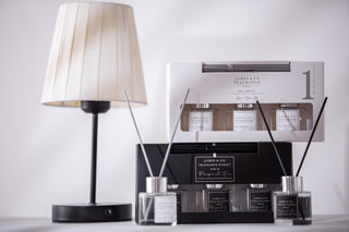 A trio of NO.1 white fragranced reed diffuser set sitting on top of a Black fragranced reed diffuser set, the fragrance is pomegranate noir.