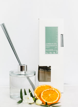 Our No. 5 Green 300ml reed diffuser sits next to cotton flowers and orange slices