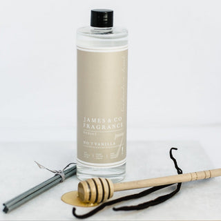 Our No. 7 Vanilla 100ml reed diffuser sat with vanilla pods and a wooden honey dipper covered in honey.