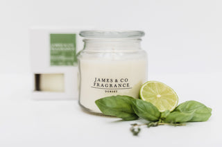 A glass jar candle with its lid on, sitting against a white background with its box in the background.