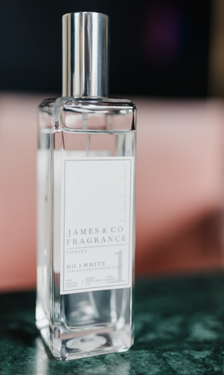 A clear bottle of room spray with a silver lid. The scent is described as No.1 White