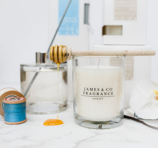 A white jar candle with the James and Co logo on the front, with the box and a reed diffuser behind it.