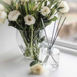 A No.1 White diffuser sat next to a vase on a counter with flowers nearby