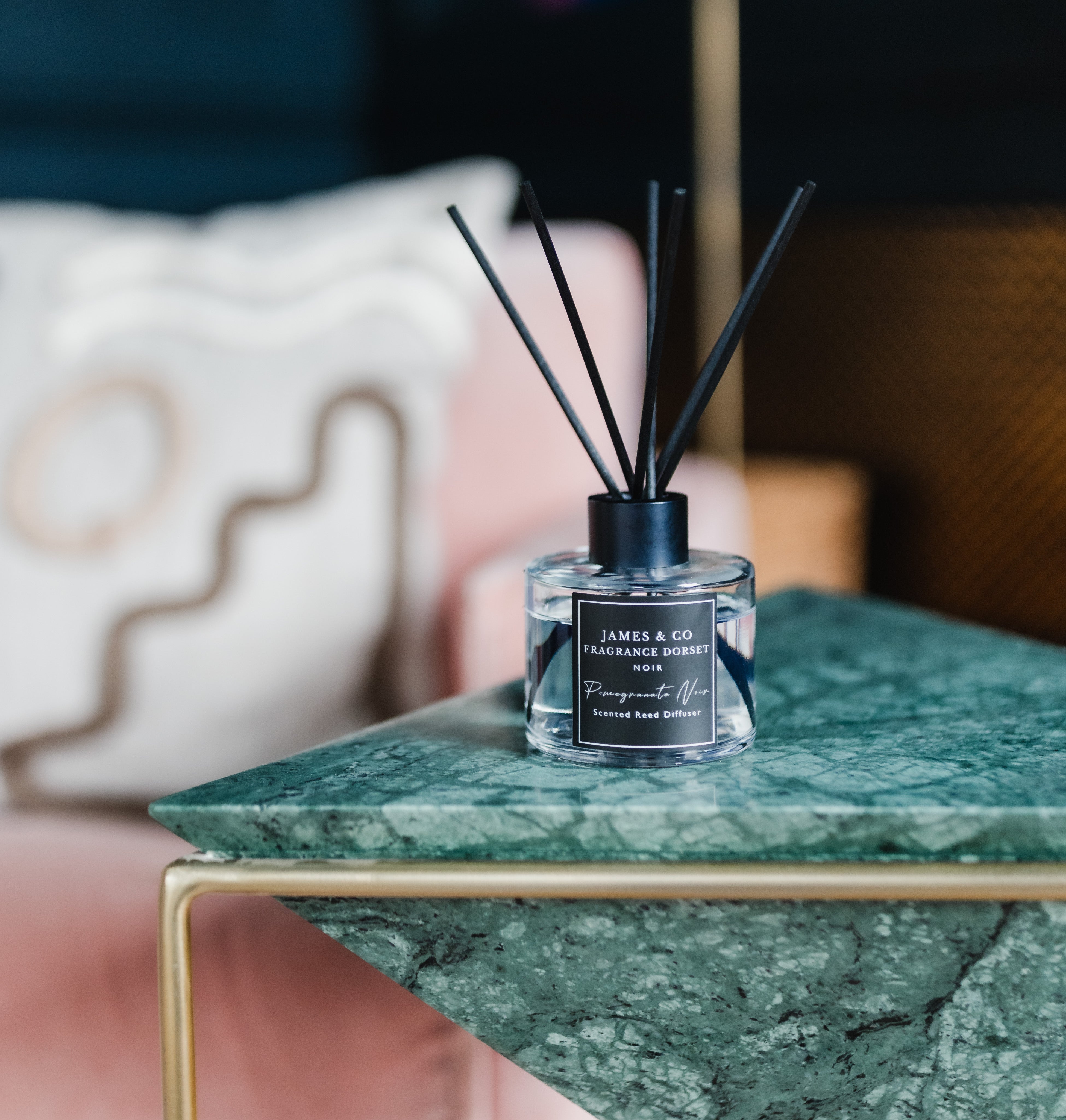 A black styled reed diffuser sat on a green marble table