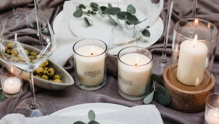 Table setting with candles, glasses, and appetizers on a wooden table.