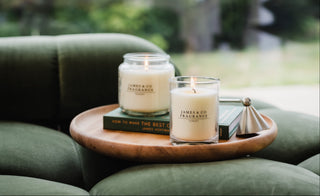 Two candles on a wooden tray with a blurred outdoor background