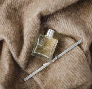 Perfume bottle with a ribbon on a textured beige fabric background