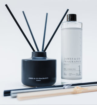 Black diffuser with reeds and a bottle of James & Co fragrance on a white background
