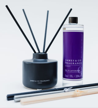 Reed diffuser set with black container and black and white sticks, alongside a purple bottle labeled 'James & Co Fragrance'.