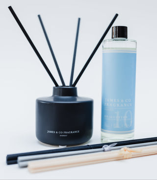 Black diffuser vessel and a blue cotton refill stood on a white background