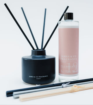 Reed diffuser set with black container and pink bottle on a white background