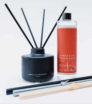 Black diffuser with reeds and a bottle of James & Co fragrance on a white background
