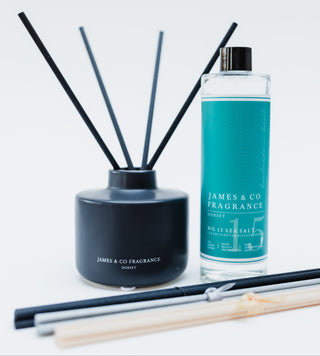 Reed diffuser set with black container and teal bottle labeled 'James & Co Fragrance' on a light gray background.