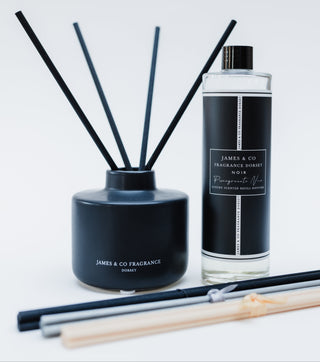 Black ceramic bottle stood next to a black diffuser refill on a white background