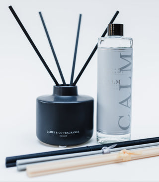Black diffuser bottle next to a Calm diffuser refill on a white background
