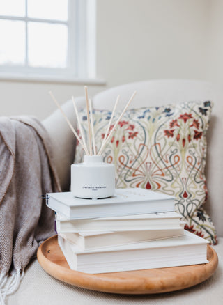 Diffuser on a stack of books with a decorative pillow in the background