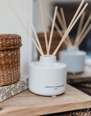 White diffuser with wooden sticks on a wooden surface, with a blurred background