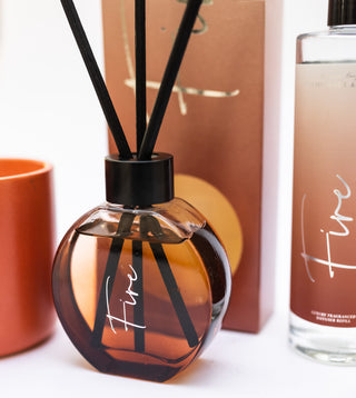 Diffuser bottle with black sticks and a box in the background