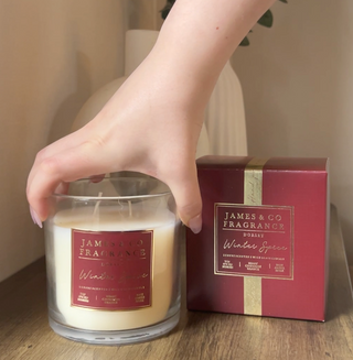 An influencer holding the winter spice 2-wick candle as they place it on a surface