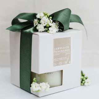Fragrance bottle packaging with green ribbon and flowers on a white background