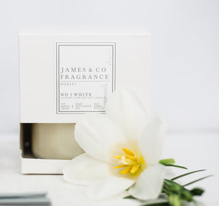 A no.1 white candle, in its box, with a lily laid in front of it.