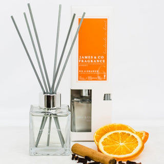 Our No. 6 Orange 100ml reed diffuser sat with sweet tangerine slices, cinnamon sticks, and a handful of cloves