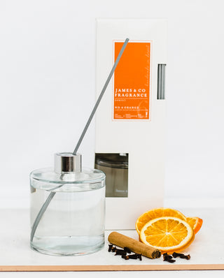 Our No. 6 Orange 300ml reed diffuser sat with sweet tangerine slices, cinnamon sticks, and a handful of cloves