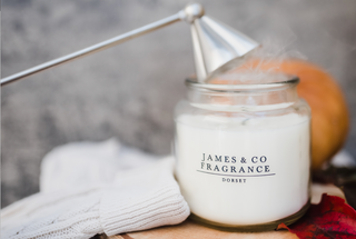 A white glass jar candle which is smoking after having been snuffed.